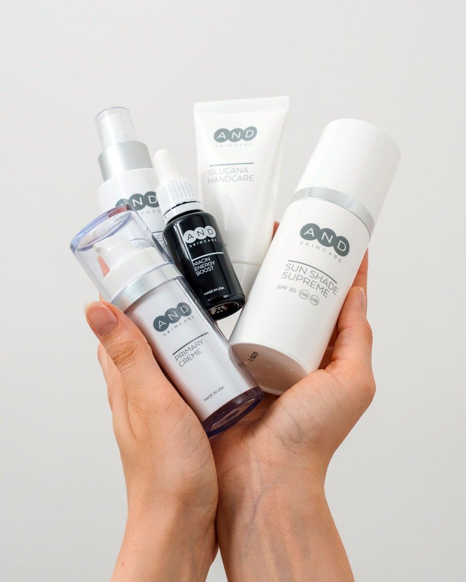 Hände halten mehrere Produkte der AND skincare Pflegeserie